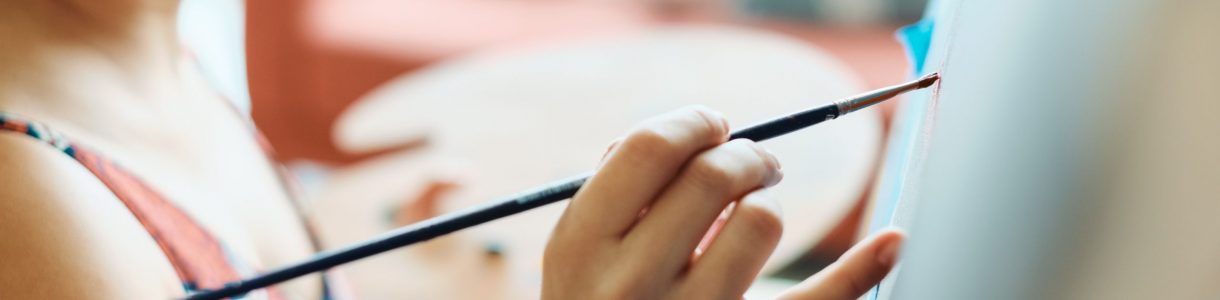 Portrait of hispanic young woman painting in her home studio, exercising with paint, brush, easel and color for hobby.